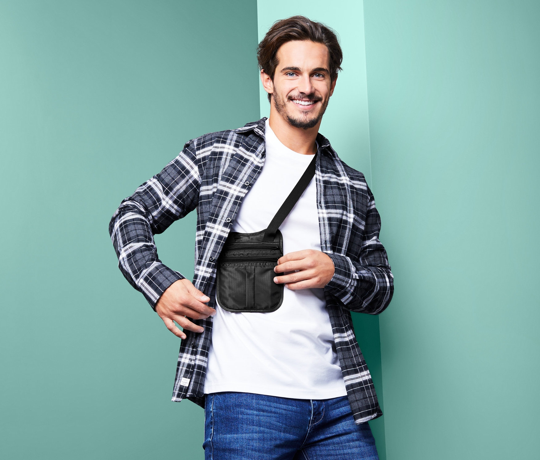 Uśmiechnięty mężczyzna pozuje z czarną bezpieczną saszetką z paskiem na ramię.