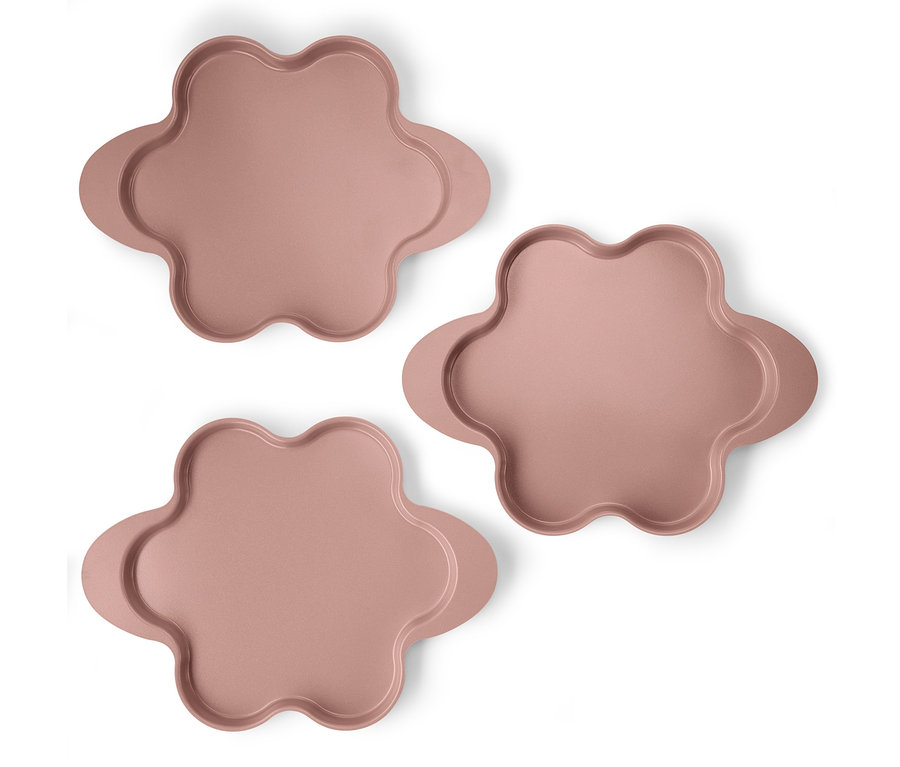 Trzy różowe formy do pieczenia ciasta z kilkoma różnymi warstwami.