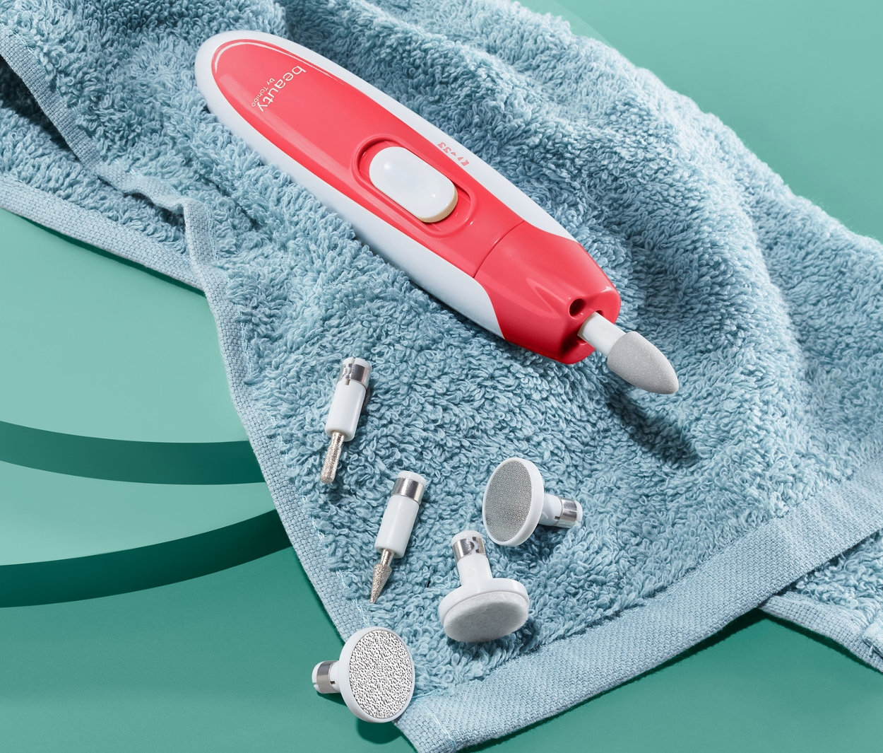 Na niebieskim tle leży niebieski ręcznik, na którym leży urządzenie do manicure i pedicure oraz kilka nasadek.