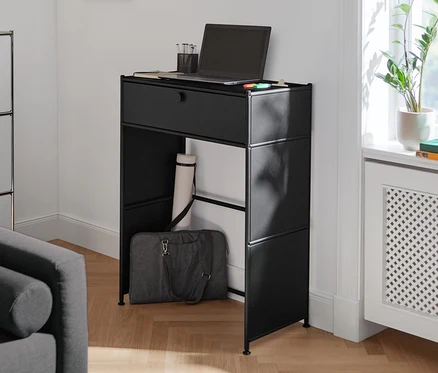Czarna metalowa konsola »CN3« z szufladą, na której stoi laptop i szklanka.