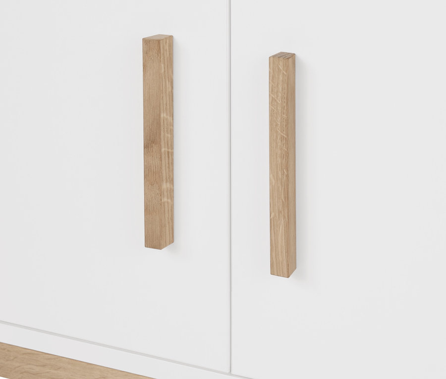 Zbliżenie na białą szafę garderobianą »Eklund« z drewnianymi uchwytami.