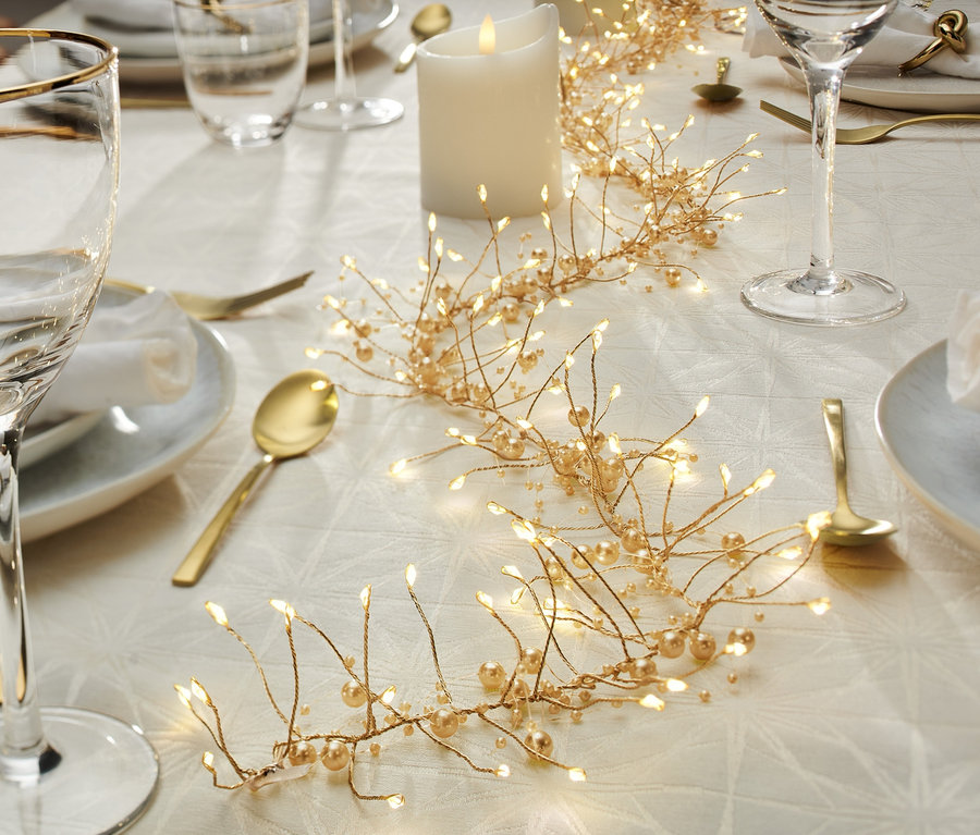 Świątecznie nakryty stół z girlandą LED.