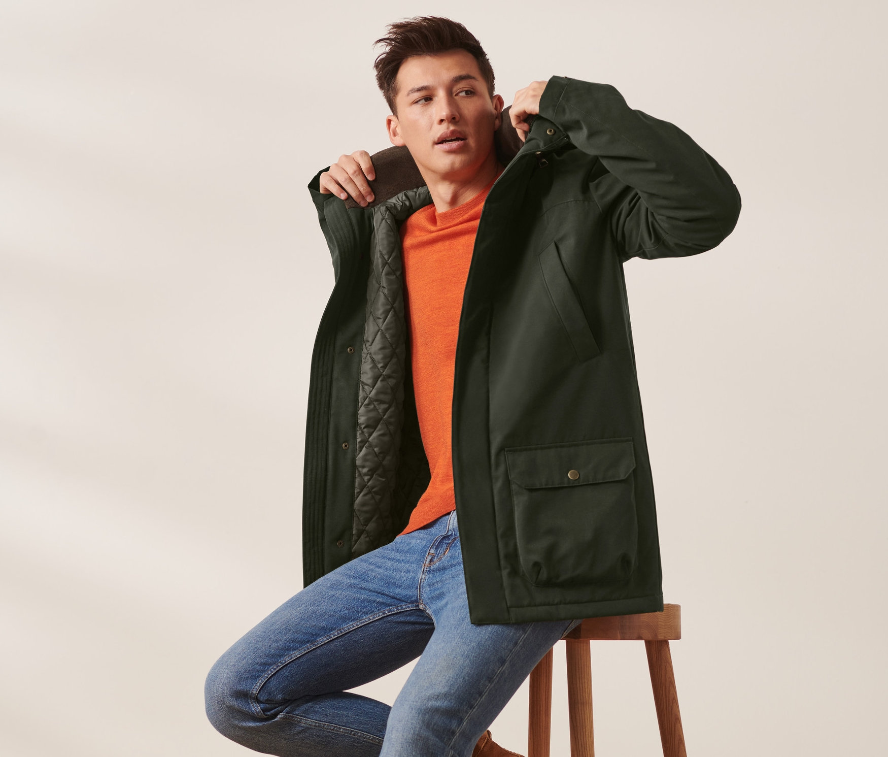 Mężczyzna siedzi na stołku i ma na sobie kurtkę.