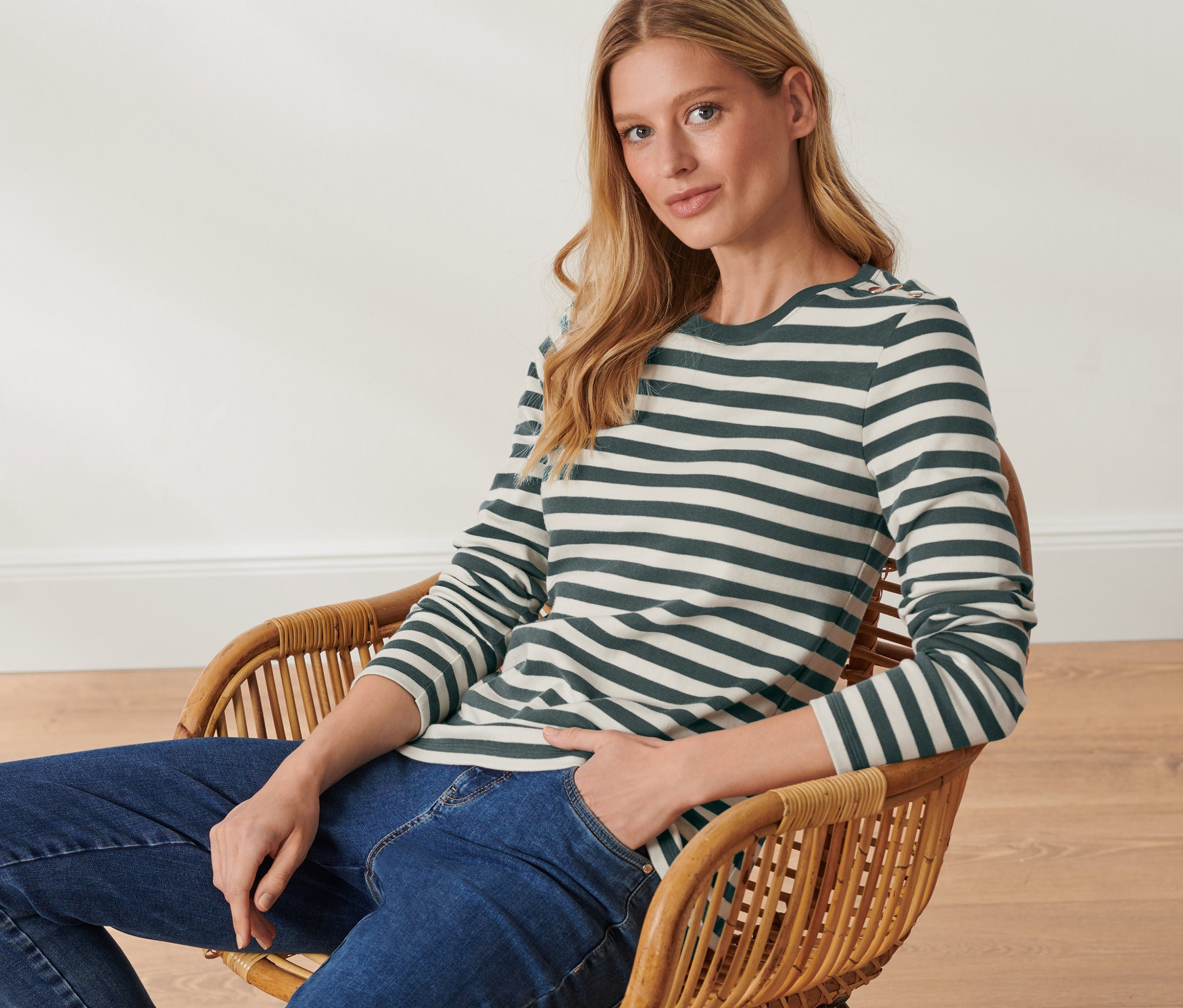 Kobieta siedzi w fotelu i ma na sobie bluzkę w paski.