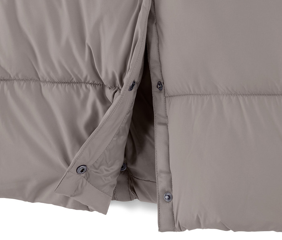Zbliżenie na szarobeżowy płaszcz pikowany z kapturem, częściowo rozpięty.