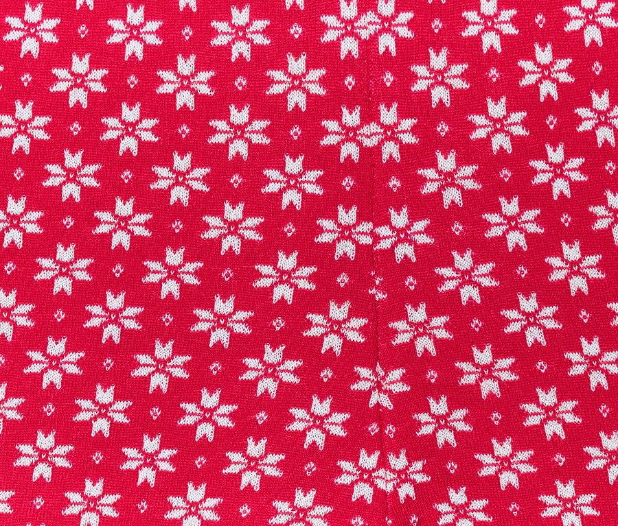 Zbliżenie na czerwone legginsy z dzianiny w białe płatki śniegu.