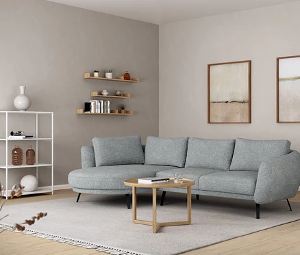 Salon z szarą sofą, okrągłym stolikiem, metalowym regałem i półką ścienną o długości ok. 120 cm.