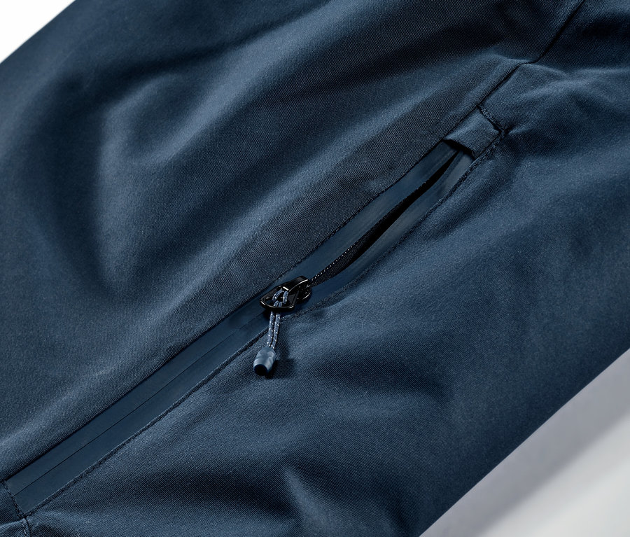 Zbliżenie na granatowe spodnie narciarskie i snowboardowe z kieszenią na zamek błyskawiczny.