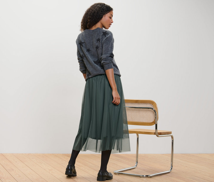 Kobieta stoi i ma na sobie spódnicę z tiulu.