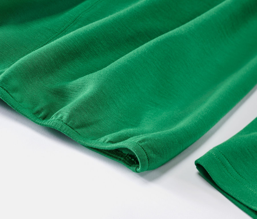 Zbliżenie zielonej bluzki z mieszanki modalu na białym tle.