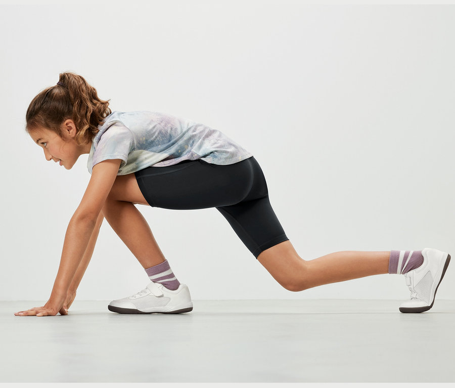 Dziewczyna w pozycji sportowej ma na sobie czarne kolarki, 2 pary.