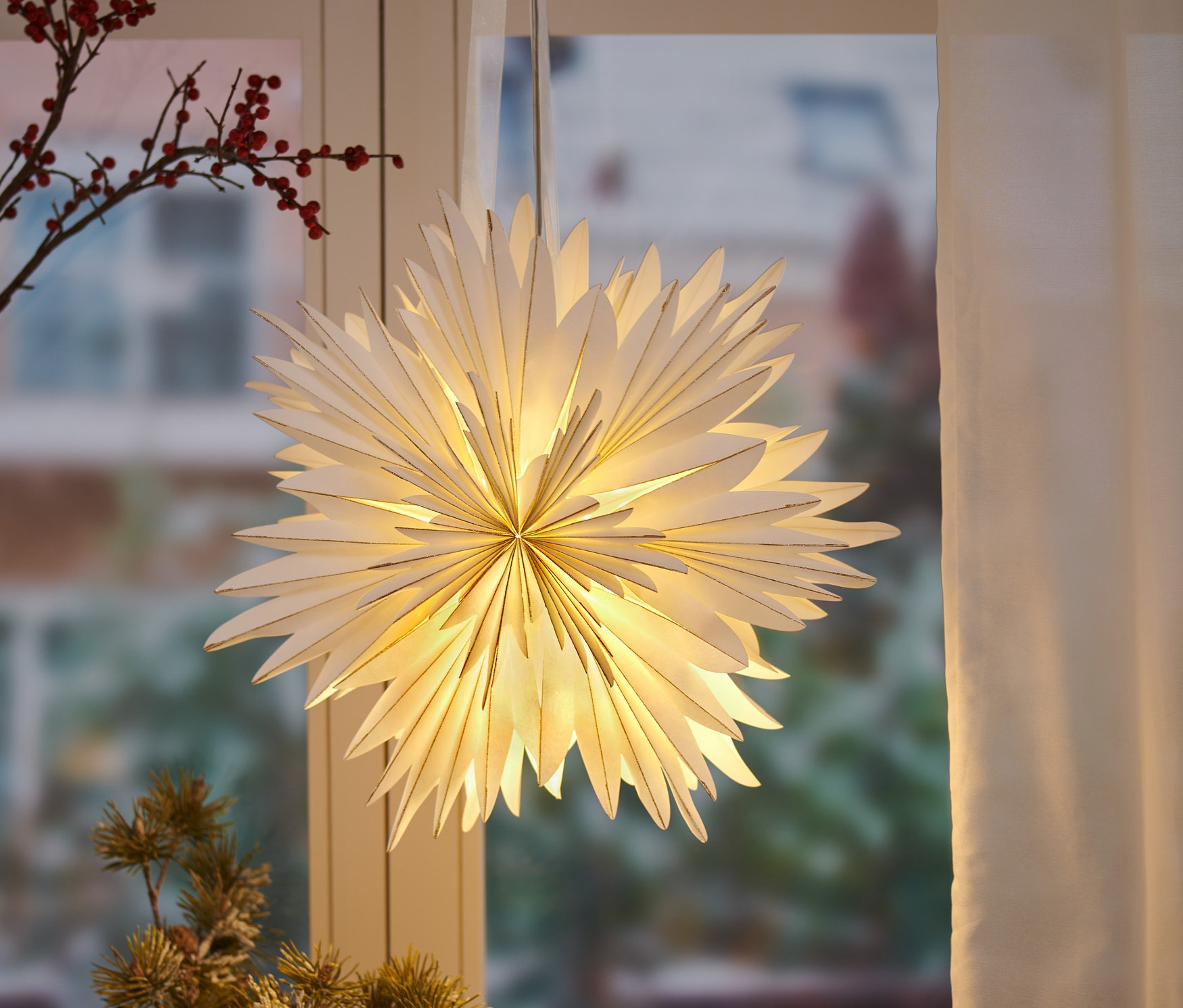 Papierowa gwiazda LED zwisa przy oknie.