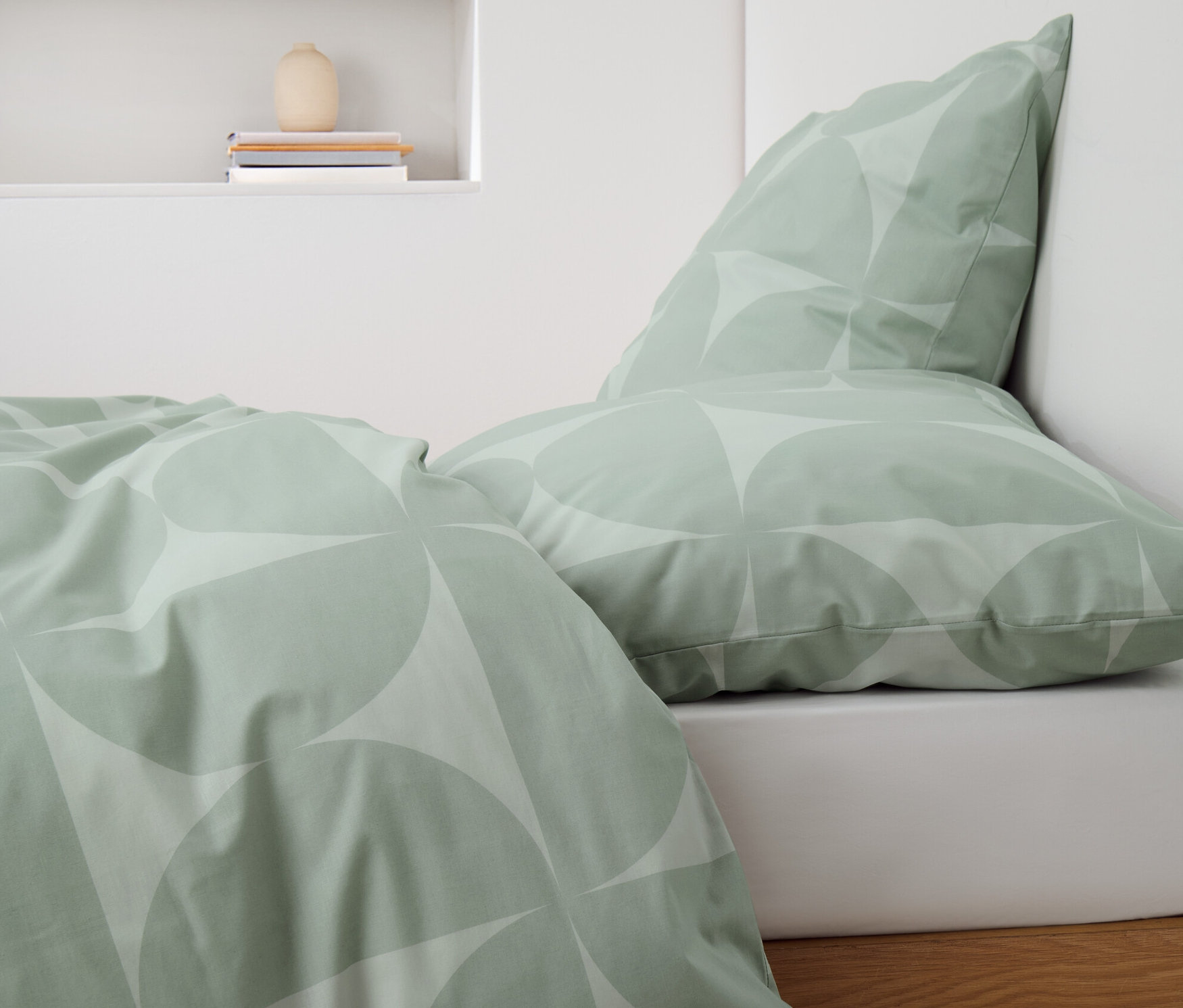 Zielona pościel z bawełny renforcé w geometryczny wzór na łóżku.