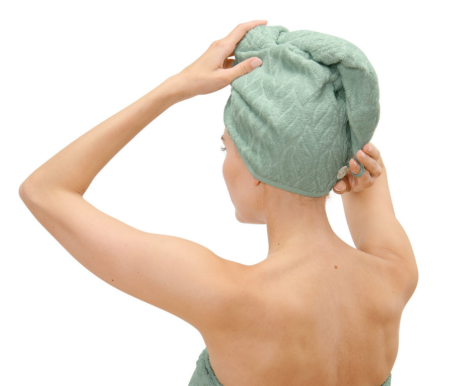 Kobieta poprawia ręcznik-turban na głowie.
