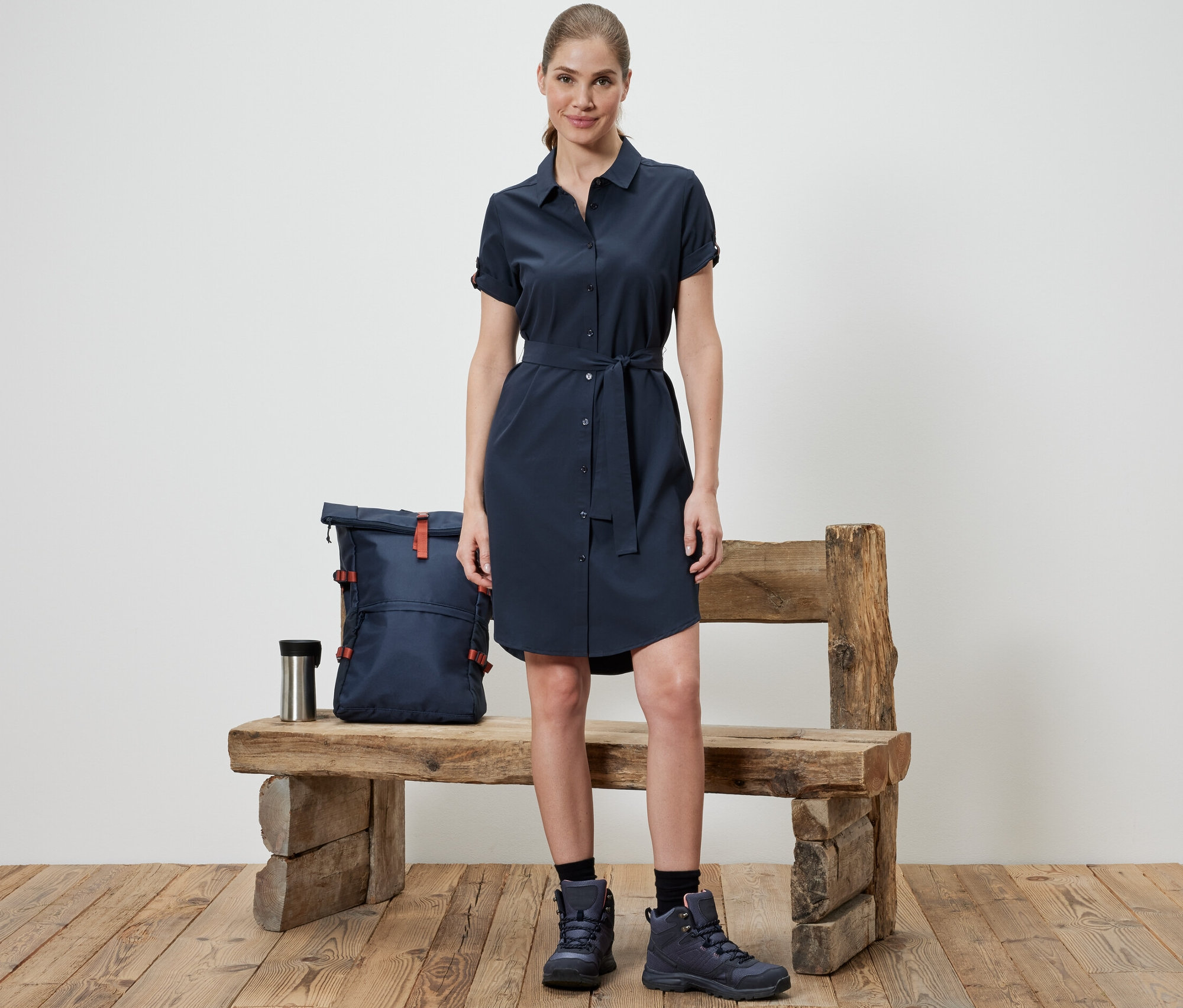 Kobieta stoi przed ławką, ubrana w sukienkę funkcyjną.