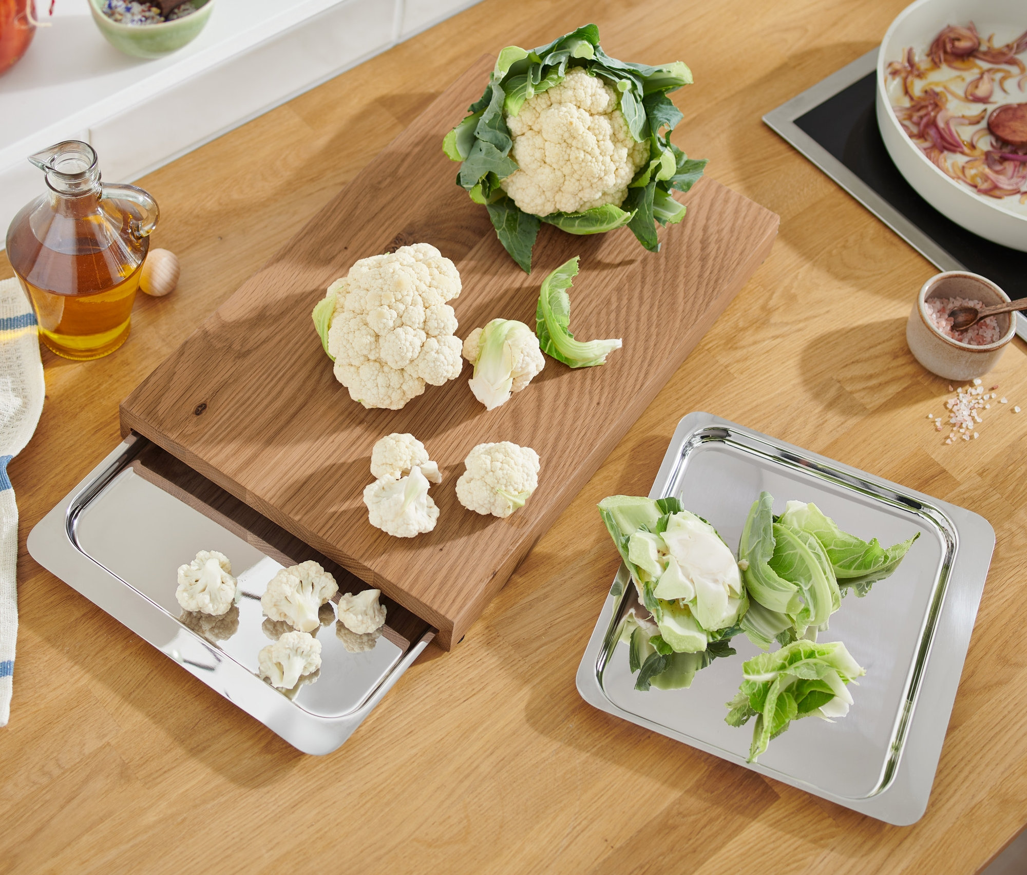 Kalafior i pokrojone kawałki na desce do krojenia i tacach ze stali nierdzewnej.