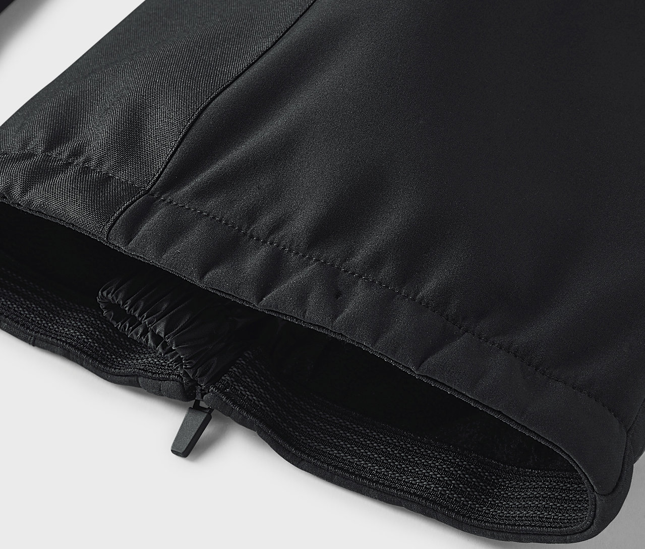 Szczegół czarnych spodni z zamkiem błyskawicznym i elastycznym obszyciem.