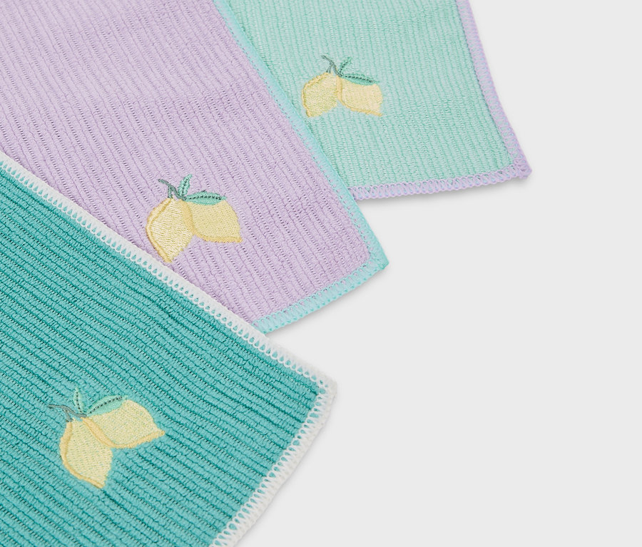 Zbliżenie na trzy kolorowe serwetki materiałowe z haftem cytryn.