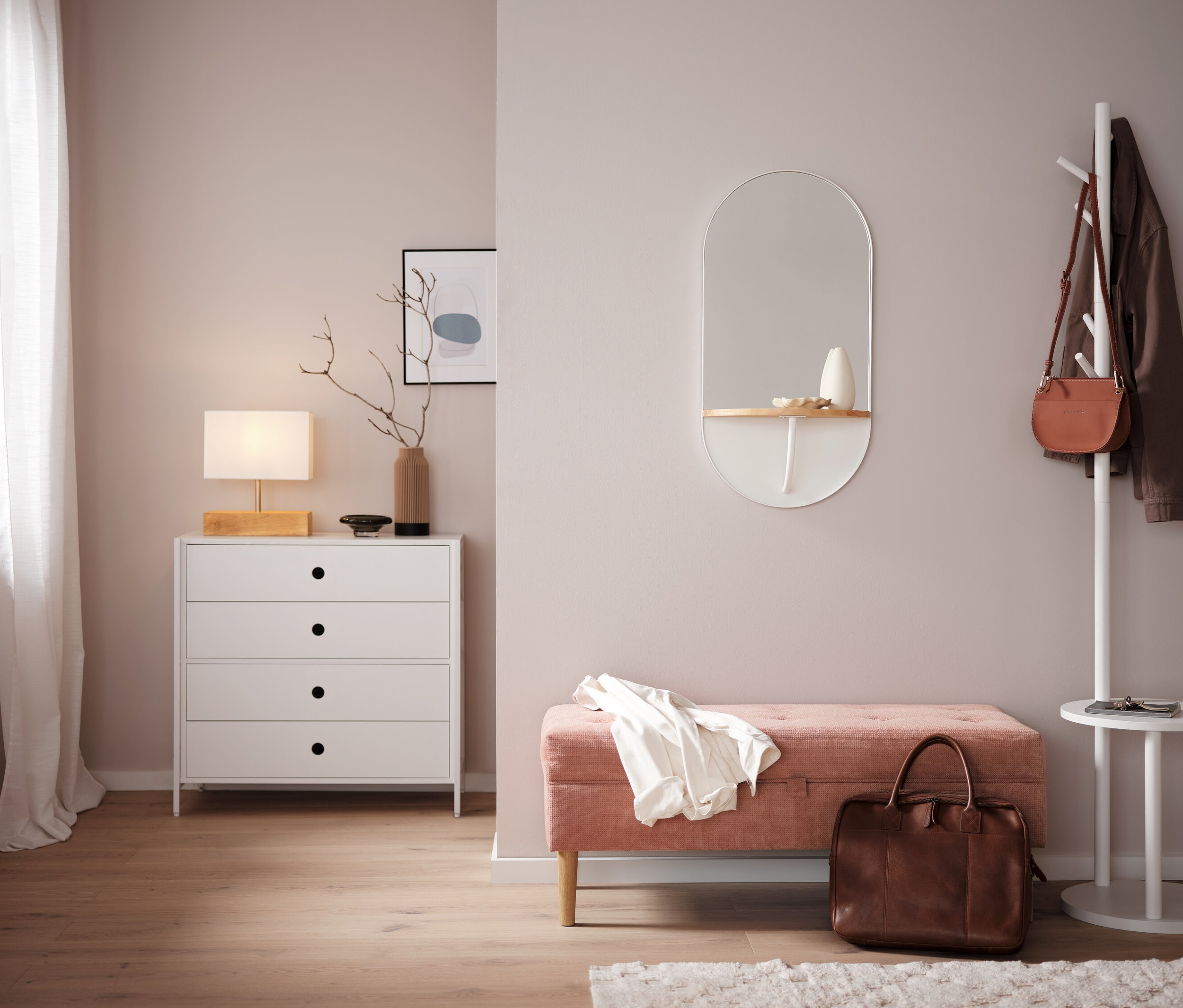 Sypialnia z białą komodą, lustrem i różową ławką.
