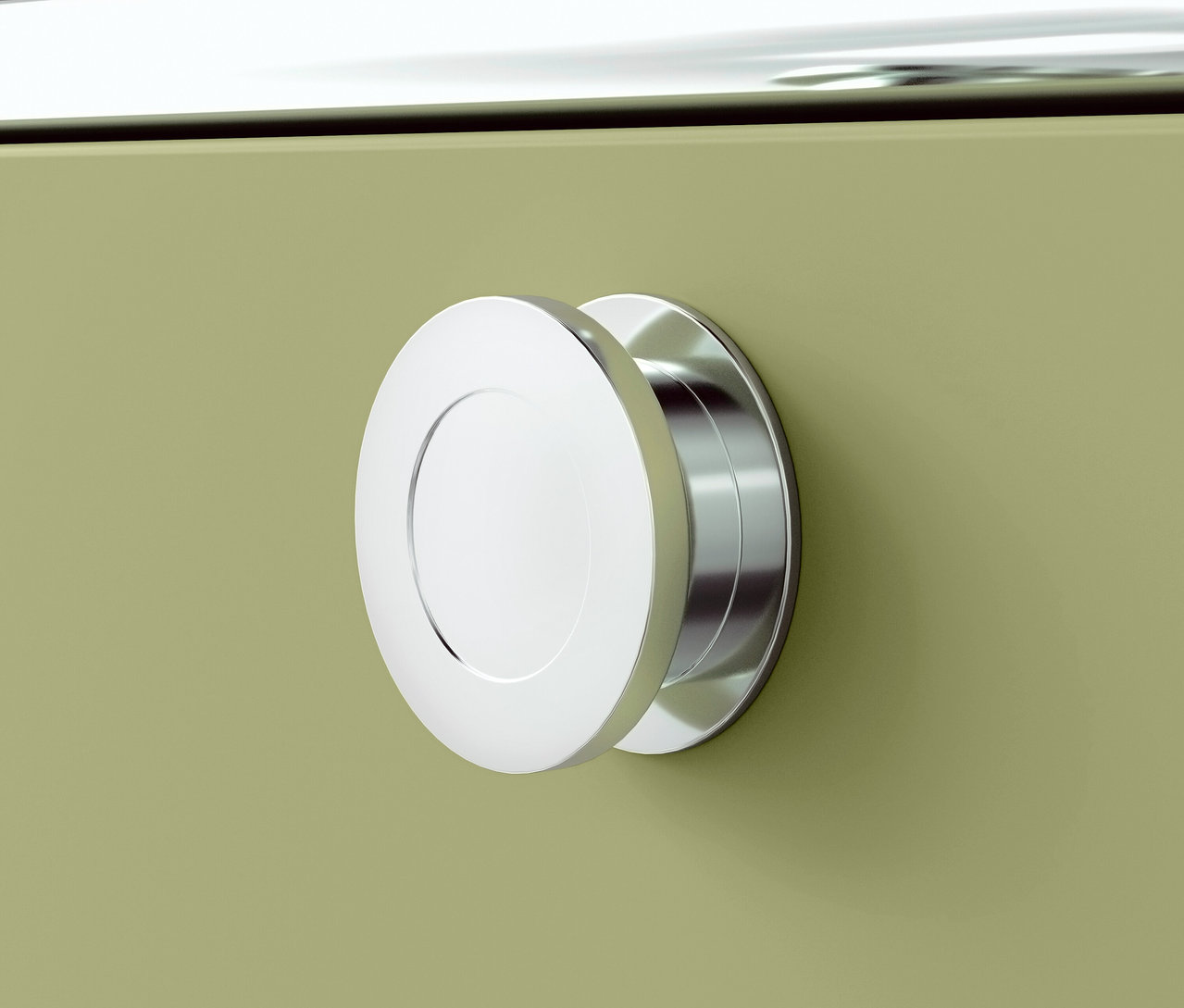 Zbliżenie chromowanego, okrągłego uchwytu na zielonej szafce.