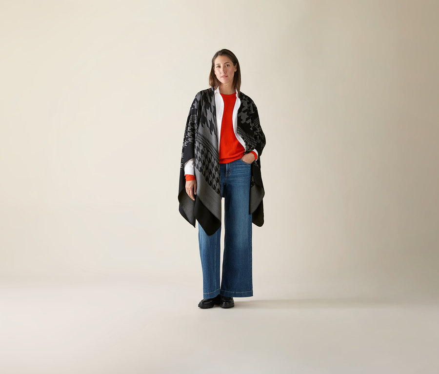 Kobieta stoi i ma na sobie pomarańczowy, cienki sweter z wełny merino.