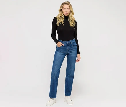 Kobieta pozuje w jeansach Angels „Lara” Straight Fit, niebieskich i czarnym golfie.