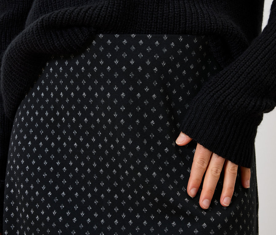 Zbliżenie na czarną spódnicę damską z drobnym wzorem i czarny sweter.