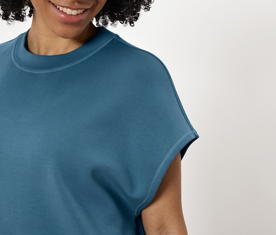 Uśmiechnięta kobieta w turkusowej koszulce.