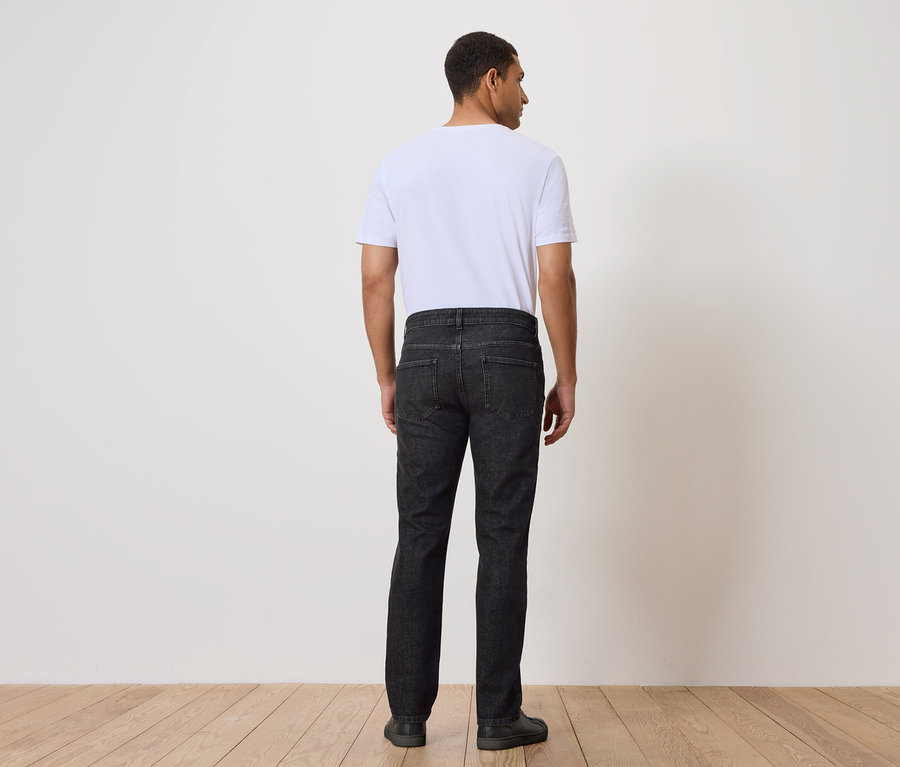 Mężczyzna tyłem do aparatu ma na sobie dżinsy i t-shirt.