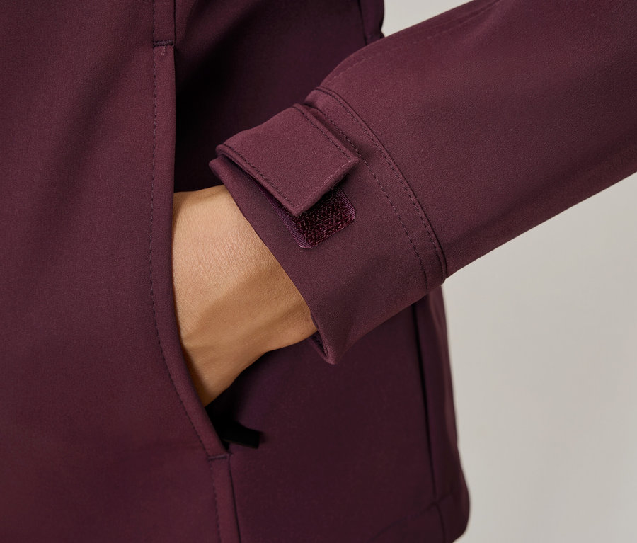 Ręka w kieszeni bordowej kurtki, detale takie jak mankiet na rzep.