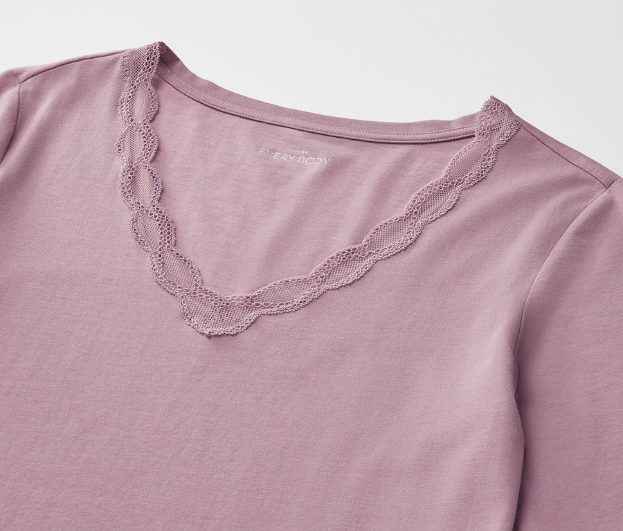 Zbliżenie na fioletową koszulkę z długim rękawem i dekoltem w szpic wykończonym koronką.