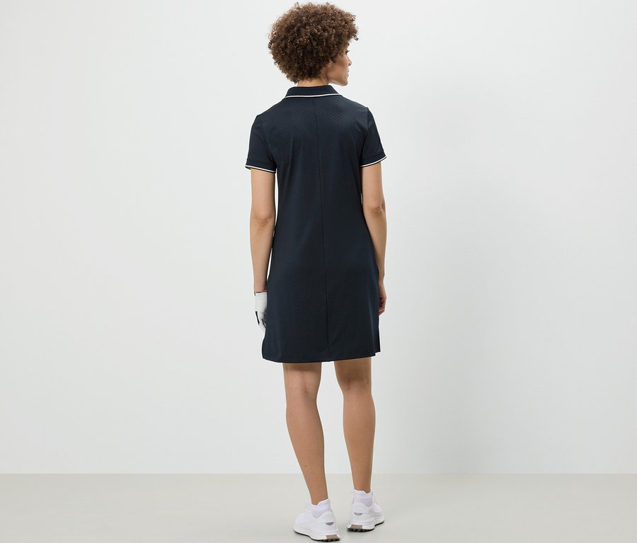 Kobieta stoi tyłem w sukience sportowej.