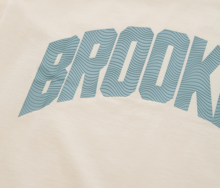 Zbliżenie kremowej koszulki z niebieskim napisem "BROOKLYN".
