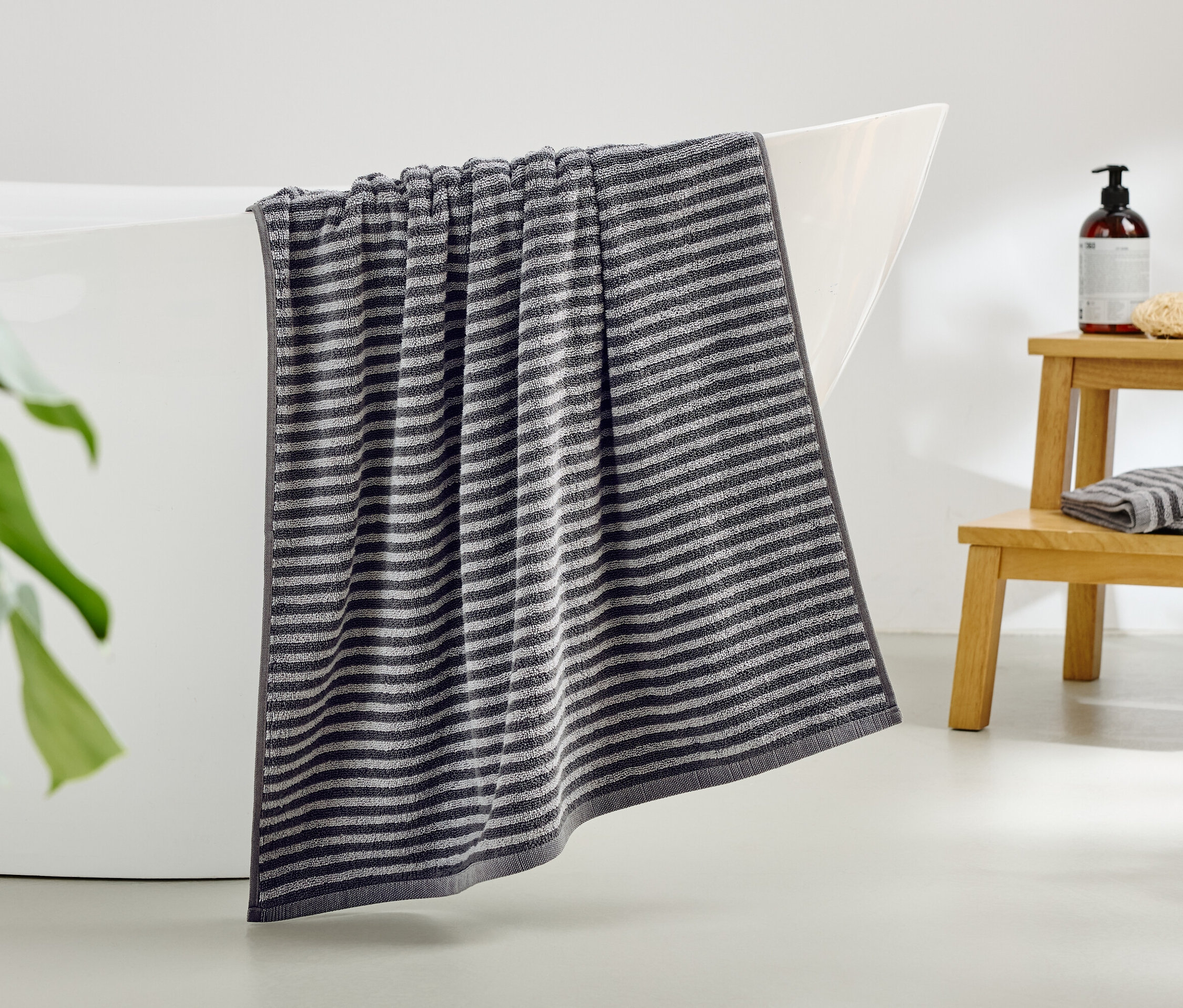 Pasiasty ręcznik zwisa z krawędzi wanny.