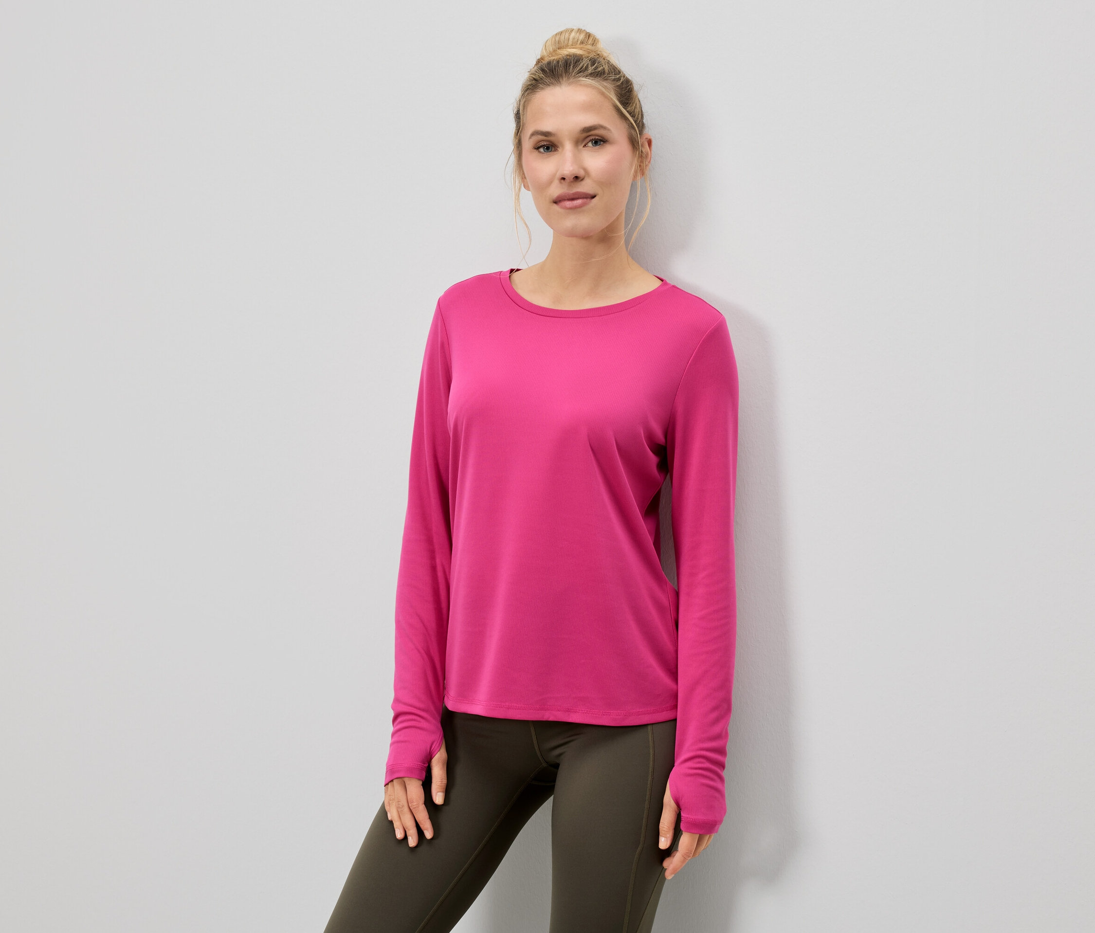 Kobieta w różowej bluzce z długim rękawem i legginsach.