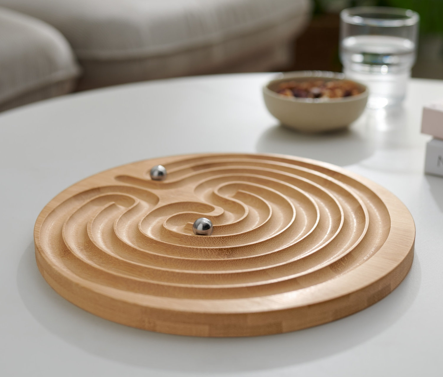 Na białym stole leży łamigłówka »Labirynt« z dwiema kulkami.