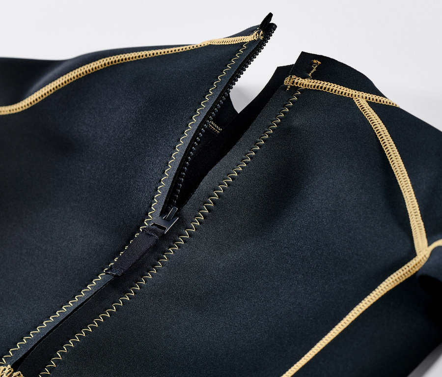 Szczegółowy widok dziecięcego kombinezonu piankowego z rozpiętym zamkiem błyskawicznym i żółtymi szwami.