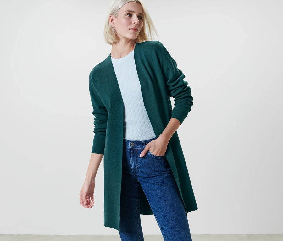 Kobieta ma na sobie niezapinany kardigan w kolorze petrol.