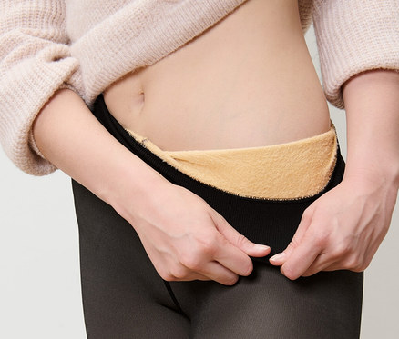 Kobieta zakłada ocieplane rajstopy z efektem przezroczystości.