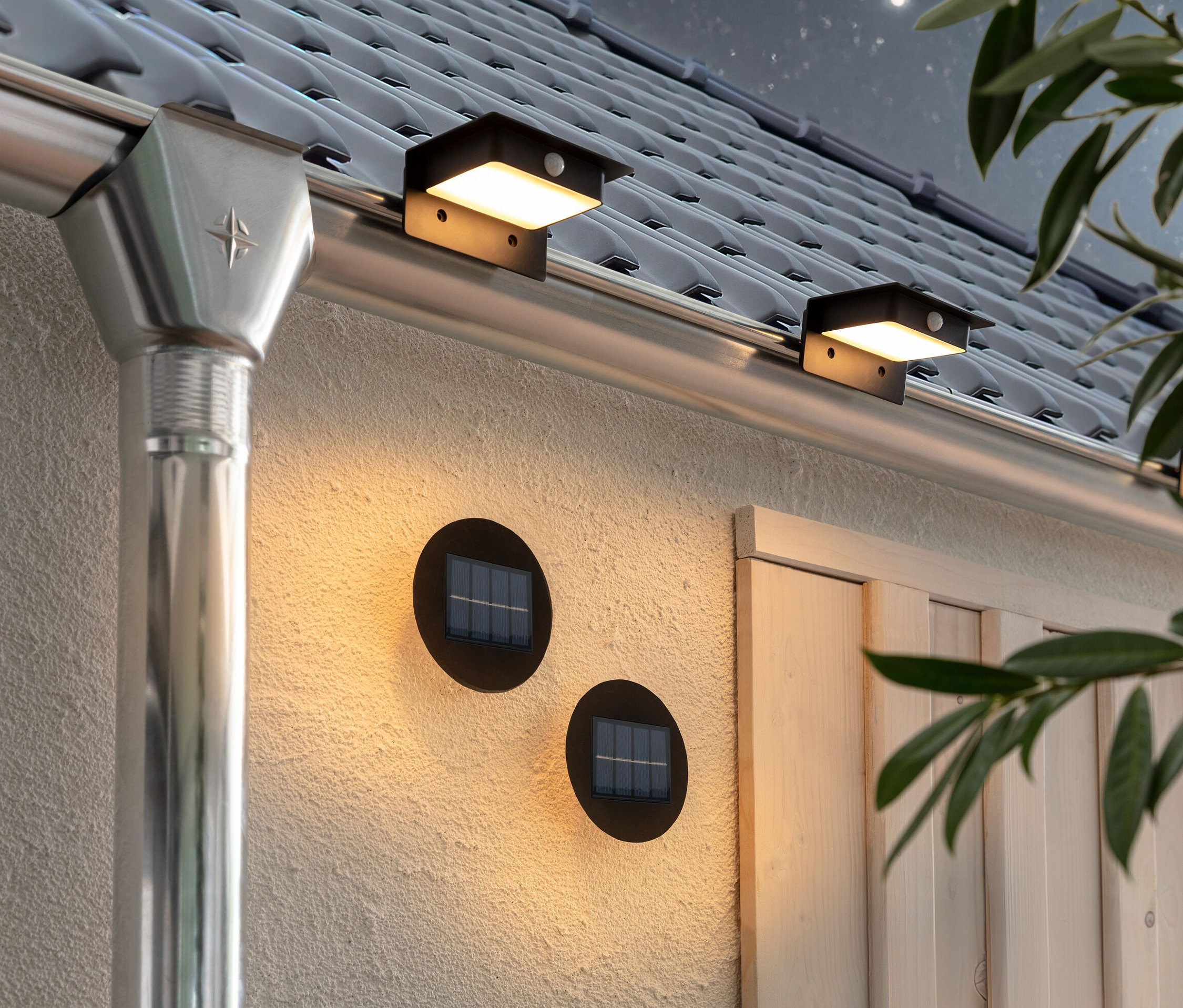 Dwie lampy do oświetlania ścian i schodów oraz trzy lampy solarne na rynnę dachową przymocowane są do ściany i rynny domu.