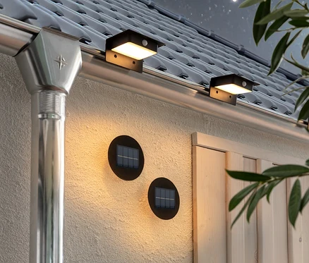 Dwie lampy do oświetlania ścian i schodów oraz trzy lampy solarne na rynnę dachową przymocowane są do ściany i rynny domu.