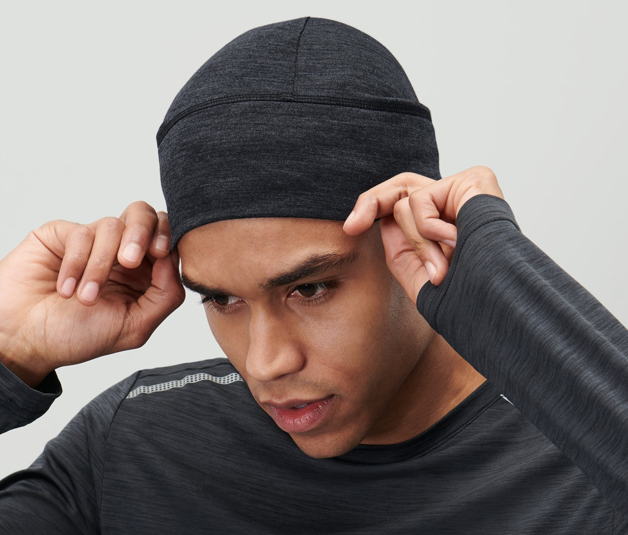 Mężczyzna poprawia czapkę z wełny merino w kolorze antracytowym na głowie.