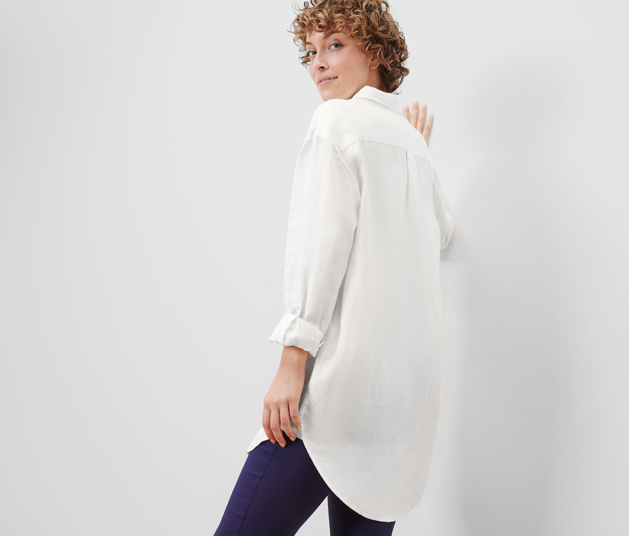 Kobieta spogląda przez ramię i pozuje w bluzce lnianej.