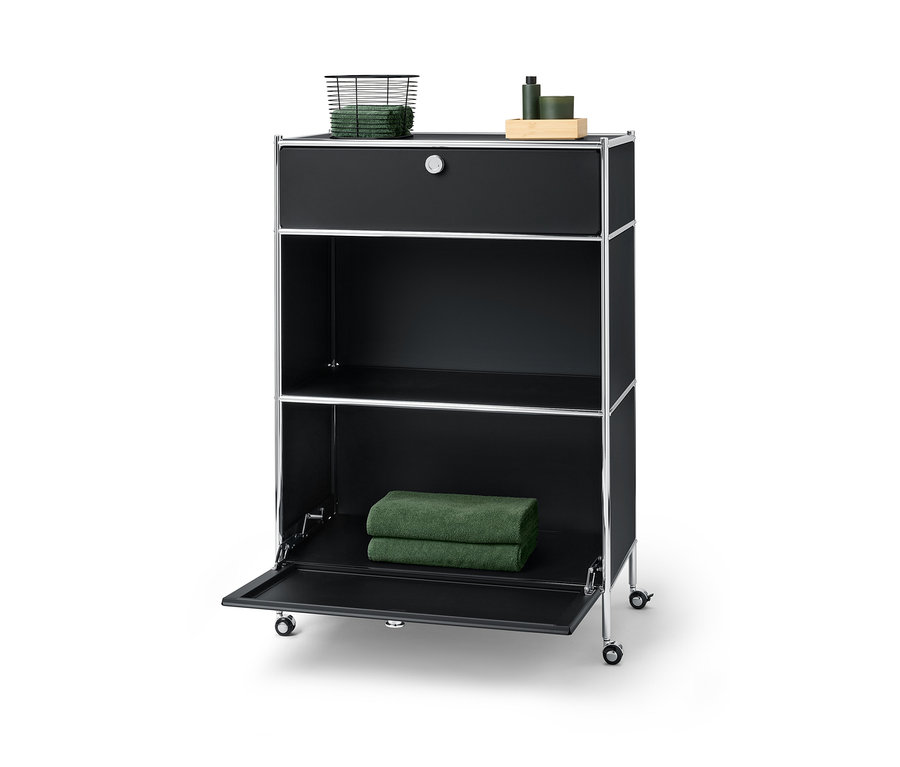 Czarna metalowa komoda „CN3” z jedną szufladą u góry, na której leży kosz z ręcznikami, i jedną klapą na dole, na której leżą dwa ręczniki.