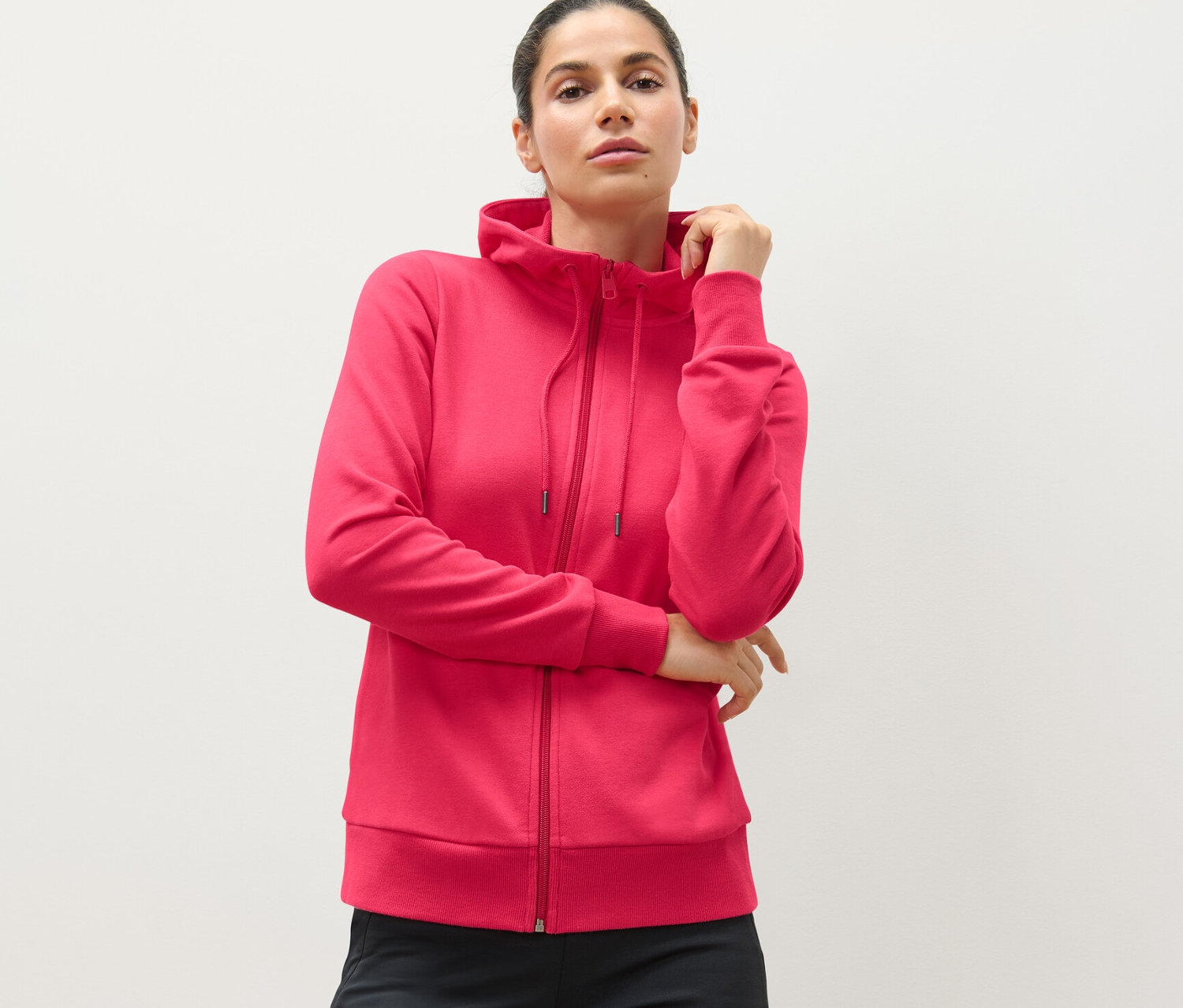 Kobieta ma na sobie różową rozpinaną bluzę dresową.