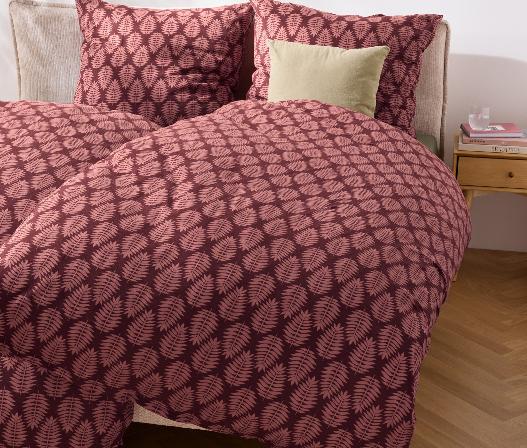 Zbliżenie łóżka z pościelą z grubego dżerseju w rozmiarze standardowym i niestandardowym we wzór z liśćmi.