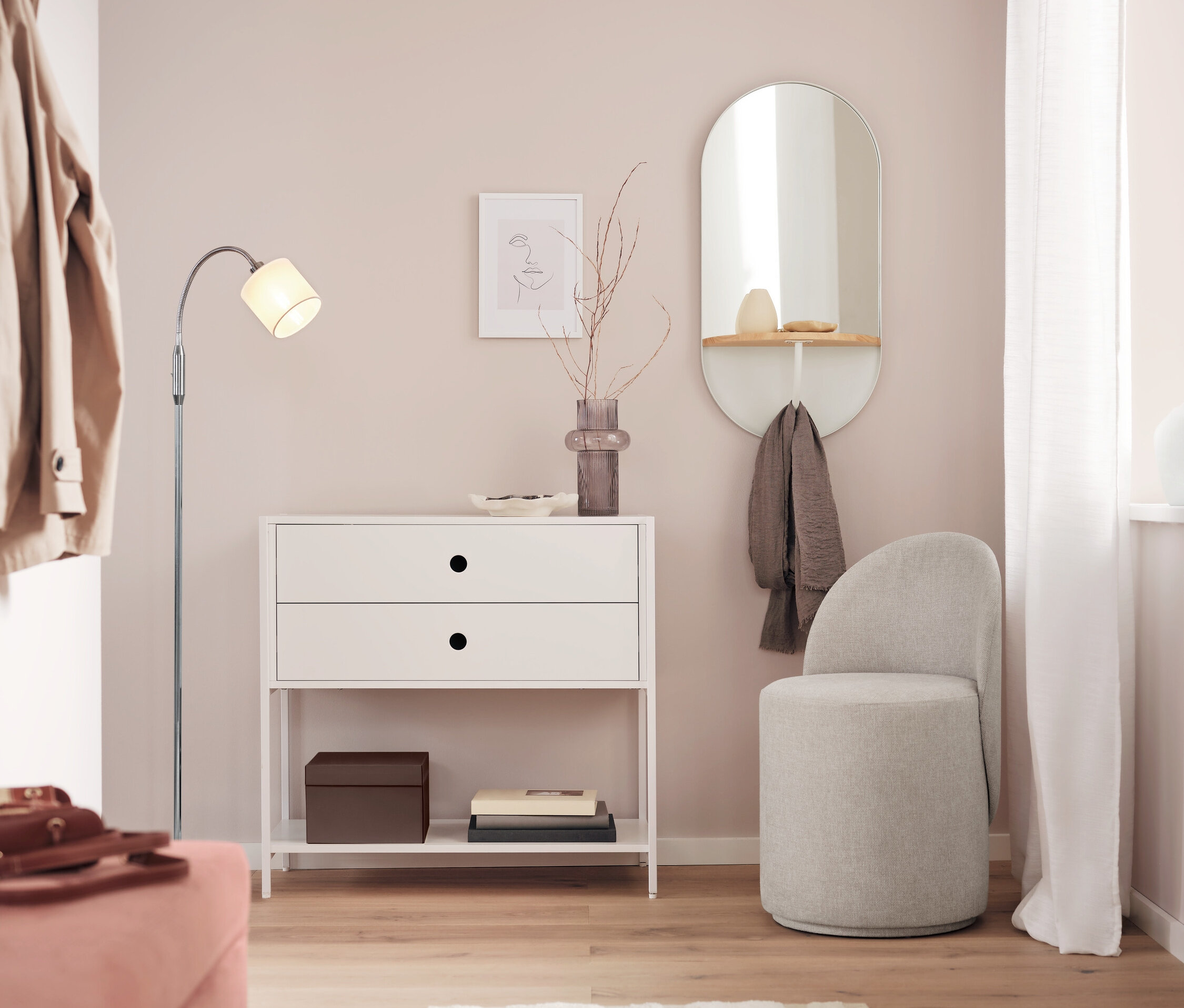 Biała komoda z dwiema szufladami stoi obok lustra i szarego stołka w pokoju.