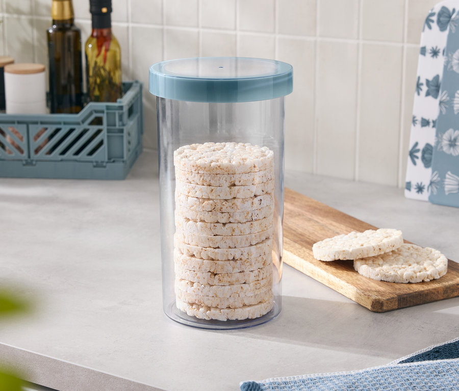 W pojemniku z niebieską pokrywką ułożono kilka wafli ryżowych, a dwa kolejne leżą na drewnianej desce.