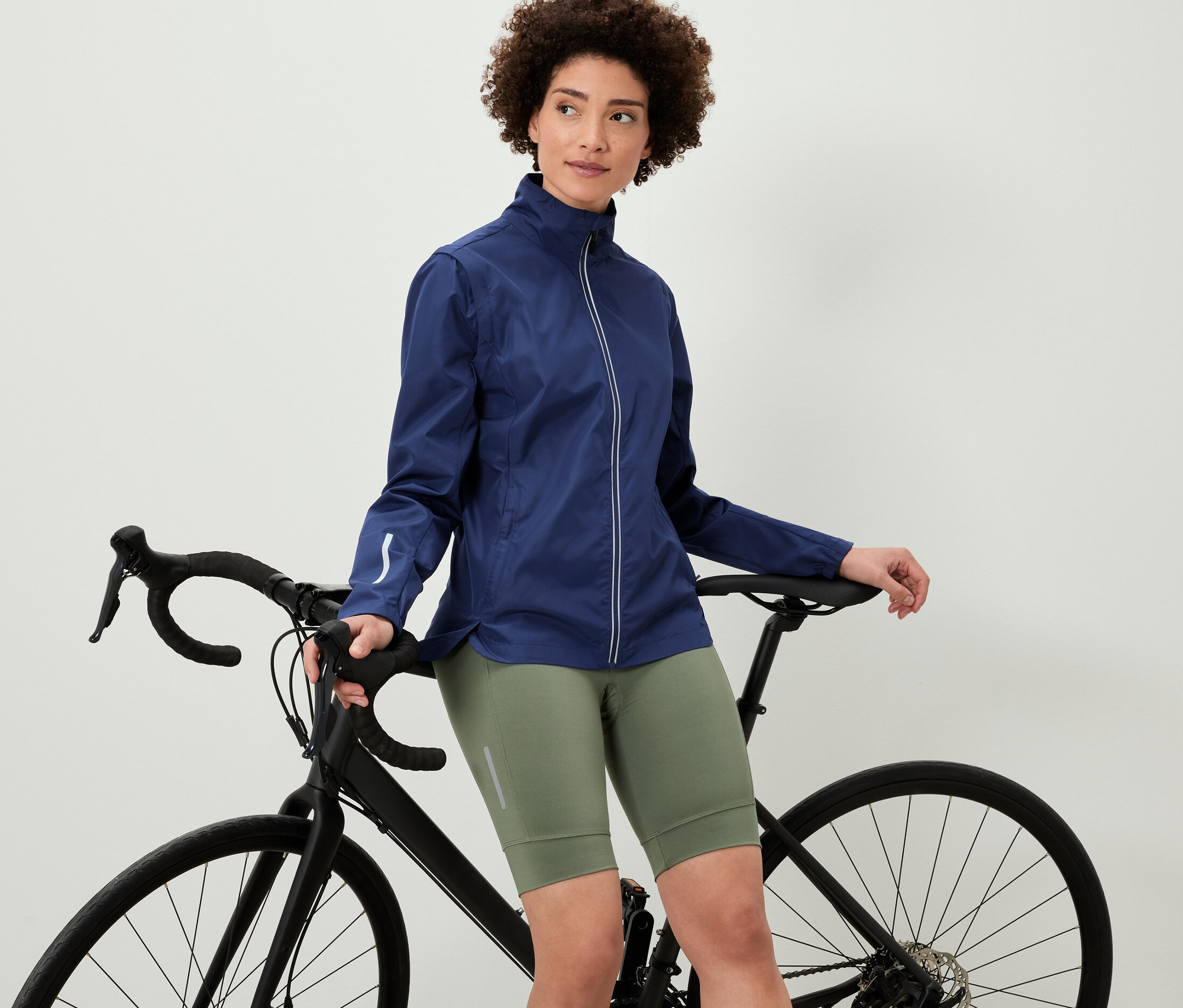 Kobieta opierająca się o rower ma na sobie kurtkę rowerową 2 w 1.