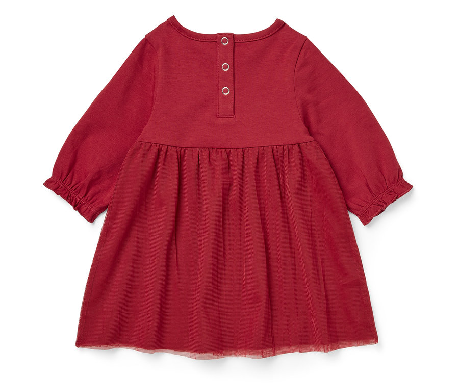 Szczegół czerwonej sukienki z długim rękawem i tiulową spódnicą.